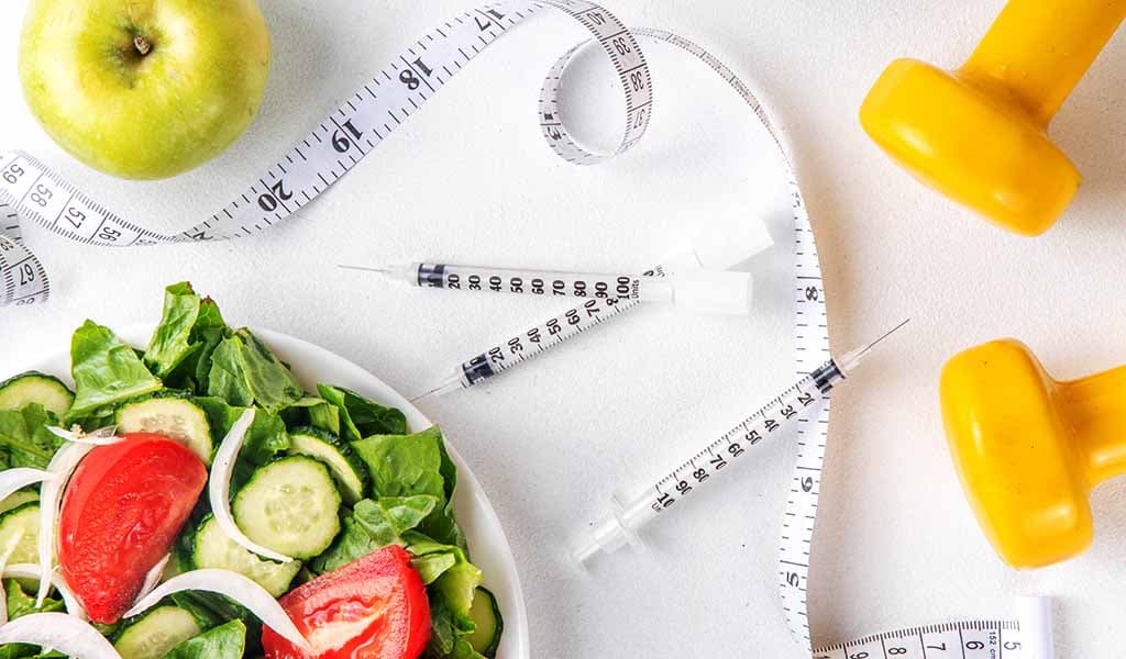 Healthy salad, syringes and dumbbells representing the standard medical weight-loss protocol at Body Slim Atlanta